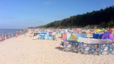 Plaża nad morzem z parasolami i upalnym słońcem, idealne miejsce na letni wypoczynek i relaks dla rodzin i turystów.