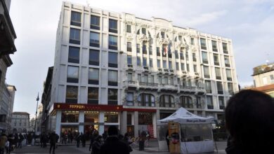 Elegancki budynek z klasyczną architekturą, z logo Ferrari na parterze, w centrum miasta z tłumem ludzi, idealne miejsce dla profesjonalistów i miłośników luksusu.