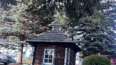 Drewniana kapliczka ogrodowa na tle drzew, symbol tradycji i duchowości, idealna do przestrzeni rekreacyjnych i edukacyjnych związanych z optymalnym rozwojem dzieci.