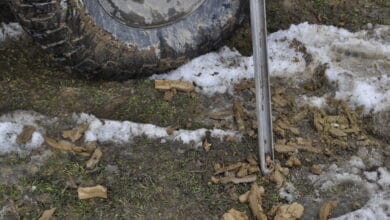 Wywóz odpadów po budowie na zielonej ziemi z błotem i tie uszkodzonymi elementami, transport ciężarówki terenowej na trudnym terenie, ekologia i recykling odpadów na placu budowy.