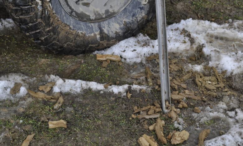 Wywóz odpadów po budowie na zielonej ziemi z błotem i tie uszkodzonymi elementami, transport ciężarówki terenowej na trudnym terenie, ekologia i recykling odpadów na placu budowy.