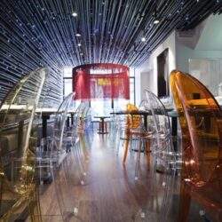 Przestronne wnętrze nowoczesnej restauracji z oryginalnym oświetleniem i designerskimi krzesłami, idealne do organizacji wydarzeń i spotkań biznesowych w centrum miasta.