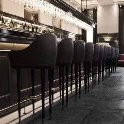 Nowy stół barowy z eleganckimi czarnymi krzesłami, minimalistycznym designem i elegancką atmosferą w nowoczesnej restauracji. Idealne miejsce na spotkania i relaks przy drinku.