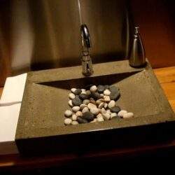 Lubiana umywalka z kamieniami i nowoczesnym kranem, eleganckie rozwiązanie do łazienki w stylu industrialnym. Idealne dla osób poszukujących unikalnych aranżacji wnętrz.