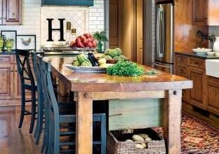 Nowoczesna kuchnia z drewnianym stołem, wyspa kuchenna i eleganckie dekoracje, idealne do przyjaznych rodzinnych spotkań i codziennego gotowania w domu.