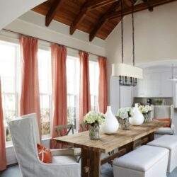 Stylowa jadalnia z dużymi oknami, białymi krzesłami i drewnianym stołem, ozdobionym bukietami kwiatów, pod wysokim drewnianym sufitem, idealne miejsce na spotkania rodzinne i biznesowe.