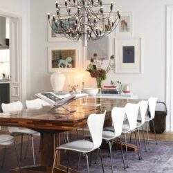 Elegancki stół konferencyjny w stylowym wnętrzu z minimalistyczną aranżacją i nowoczesnym żyrandolem, idealny do spotkań biznesowych i wydarzeń firmowych w eleganckim otoczeniu.