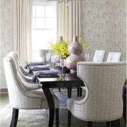 Elegancki jadalniany stół z białymi tapicerowanymi krzesłami, dekoracyjna aranżacja wnętrza z kwiatami i lampą sufitową, idealny do eleganckich spotkań i rodzinnych obiadów.