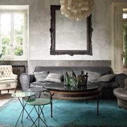 Stylowy salon w stylu vintage z naturalnym światłem i wygodną sofą, idealny do relaksu i spędzania czasu z rodziną, z roślinami i eleganckimi dekoracjami.