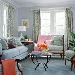 Przytulny salon z dużymi oknami i kolorowymi zasłonami, eleganckie meble tapicerowane, dekoracyjne poduszki, rośliny ozdobne, idealne miejsce do relaksu i spotkań rodzinnych.