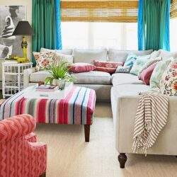 Przytulny salon z dużą sofą, kolorowymi poduszkami i eleganckim żyrandolem, idealny do relaksu i spotkań towarzyskich, ozdobiony roślinami i modnymi tekstyliami dla komfortu.