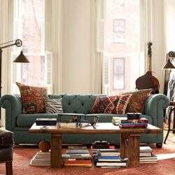 Przytulny salon z dużym oknem, klasyczną sofą i dekoracyjnymi poduszkami, idealny do relaksu i spotkań z rodziną.