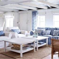 Przytulny salon z białymi kanapami, niebieskimi poduszkami i naturalnymi elementami wystroju, idealny do relaksu i spotkań w domowym zaciszu.