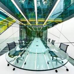 Nowe, nowoczesne centrum konferencyjne z dużym, szklanym stołem i wygodnymi krzesłami w eleganckiej, przeszklonej sali biznesowej. Idealne miejsce na spotkania i negocjacje.