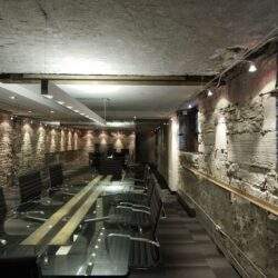 Nowoczesne biuro w stylu industrialnym z ceglaną ścianą i eleganckim stołem konferencyjnym, idealne dla firm ceniących unikalny klimat i funkcjonalność.