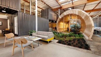 Nowoczesna strefa relaksu w biurze z komfortowym sofa, drewnianymi krzesłami i zielenią w inspirującym wnętrzu. Idealne miejsce do odpoczynku i spotkań branżowych w optymalnym środowisku pracy.