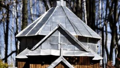 Mały drewniany kościółek z metalowym dachem na tle lasu, symbol duchowości i tradycji.