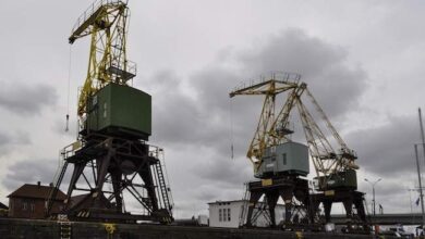 Okręty portowe na nabrzeżu, industrialne elementy krajobrazu portowego, maszyny portowe przy nabrzeżu, niezwykłe widoki na przemysłowe wyposażenie portowe, fotografia przemysłowa portu w pochmurny dzień.