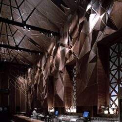 Futurystyczny wystrój wnętrza baru z drewnianymi elementami i geometrznymi zdobieniami, eleganckie oświetlenie, nowoczesna aranżacja, idealna na spotkania biznesowe i eleganckie wydarzenia.