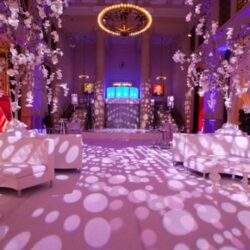 Eleganckie wnętrze sali bankietowej z delikatnym oświetleniem i kwiatowymi dekoracjami, idealne na wesela i wydarzenia firmowe – elegancka atmosfera, która podkreśla wyjątkowość uroczystości.