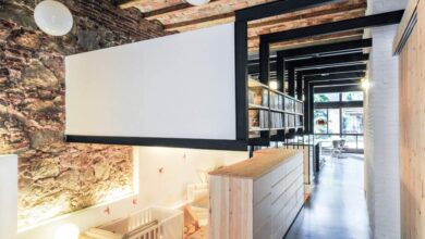 Naturalne, loftowe wnętrze z widokiem na przestronną pracownię biurową, styl industrialny, ceglana ściana, drewniane elementy, elegancka przestrzeń do pracy i relaksu, optymalne rozwiązania biurowe.