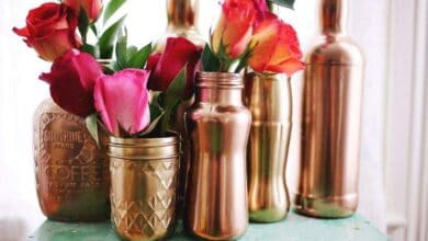 Róże w dekoracyjnych złotych wazonach na rustykalnym stole, elegancka aranżacja kwiatowa do wnętrz, stylowa dekoracja na różne okazje, luksusowe dodatki do domu.