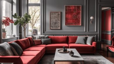 Elegancki salon z czerwonym narożnikiem, stylowe wnętrze z szarymi panelami, nowoczesne oświetlenie i dekoracje, idealne do relaksu i spotkań w eleganckim miejscu.