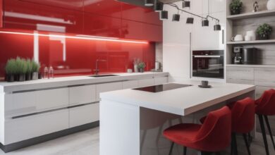 Nowe, eleganckie wnętrze kuchni z nowoczesnym designem, białymi i czerwonymi szafkami, wyspą kuchenną i stylowym oświetleniem. Idealne rozwiązania dla funkcjonalnej kuchni.