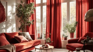 Stylowe wnętrze salonu z czerwonymi zasłonami i sofą, naturalne światło oraz dekoracje roślinne tworzą przytulną atmosferę, idealną do relaksu i spotkań, w nowoczesnym minimalistycznym stylu.