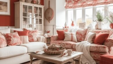 Przytulny salon w stylu rustykalnym z czerwonymi i beżowymi akcentami, eleganckie dekoracje, duże okna, wygodne kanapy, stół i naturalne dodatki, idealny do relaksu i spotkań rodzinnych.