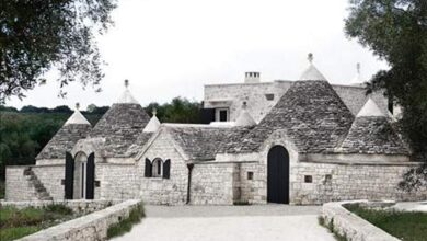 Mały zamek z cegieł i kamienia w okolicy z zielonymi drzewami, w stylu historycznej architektury. Tradycyjny styl z unikalnym charakterem, idealny dla miłośników historycznych budowli.