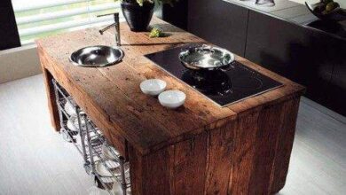 Kuchnia w stylu industrialnym z drewnianym wyspowym blatem, nowoczesne wyposażenie, czystość i funkcjonalność, idealne rozwiązanie dla miłośników minimalistycznego designu i komfortu.