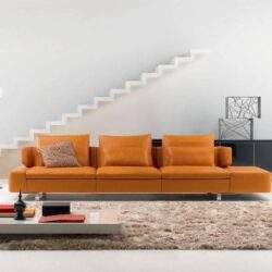 Nowe, nowoczesne wnętrze salonu z elegancką sofą w odcieniach pomarańczowego, minimalistyczną dekoracją i jasnym tłem, idealne do aranżacji wnętrz.