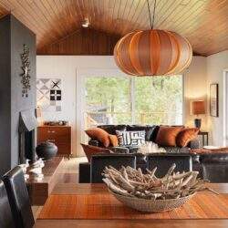 Przytulny salon z drewnianym sufitem, nowoczesnym oświetleniem, komfortową sofą i eleganckimi dodatkami w stylu skandynawskim, idealny do relaksu i spotkań z rodziną.