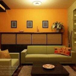 Nowoczesny salon z minimalistycznym wystrojem, elegancką sofą, pamiątkami na półkach i ciepłym oświetleniem, idealny do relaksu i spotkań w domu.