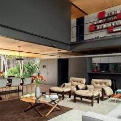 Przestronny nowoczesny salon z drewnianym sufitem, wygodną sofą i minimalistycznym wykończeniem wnętrz, idealny dla optymalnych rozwiązań aranżacyjnych.