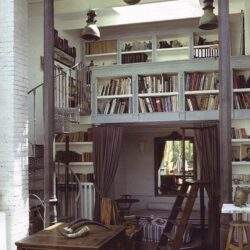 Przestrzeń do czytania z książkami i regałami, wnętrze z dużą biblioteczką, przytulna atmosfera, elegancki dom z wysokimi regałami, inspirujące miejsce do relaksu i nauki.