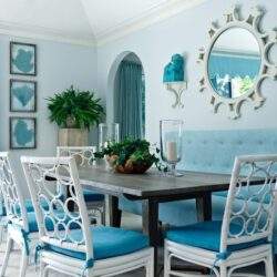 Elegancka jadalnia w stylu glamour z niebieskimi akcentami i ozdobnym lustrem, idealna do organizacji rodzinnych spotkań i uroczystości, w jasnym i przestronnym wnętrzu.