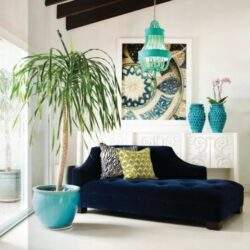 Stylowe wnętrze z elegancką sofą, dekoracyjnymi poduszkami i zielonymi roślinami, idealne do aranżacji przestrzeni w stylu optima.