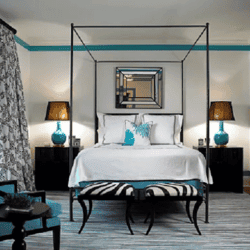 Elegancka sypialnia z nowoczesnym wystrojem, czarne i turkusowe akcenty, komfortowe łóżko i stylowe dodatki, idealne miejsce na relaks i wypoczynek.