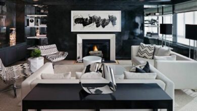 Przytulny salon z kominkiem, eleganckim wystrojem i nowoczesnym designem, idealny do relaksu i spotkań z rodziną. Jasne sofy, czarne akcenty i stylowe dodatki tworzą elegancką atmosferę.