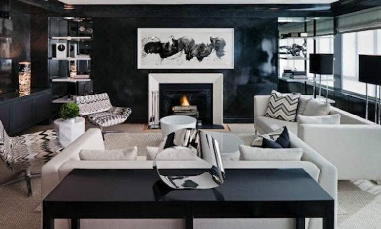 Przytulny salon z kominkiem, eleganckim wystrojem i nowoczesnym designem, idealny do relaksu i spotkań z rodziną. Jasne sofy, czarne akcenty i stylowe dodatki tworzą elegancką atmosferę.