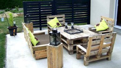 Nowe meble ogrodowe z palet drewnianych na tarasie z poduszkami i lampami do relaksu i wypoczynku pod gołym niebem.