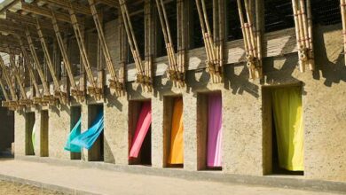 Alt: Budynek z kolorowymi oknami z zasłonami na tle konstrukcji drewnianej w centrum miasta.