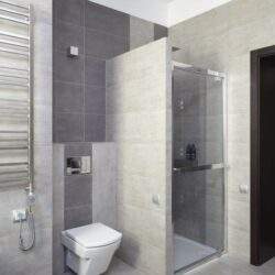 Porcelanowa łazienka z WC i kabina prysznicową, nowoczesny design, jasne i ciemne płytki, oszczędna elegancja, minimalistyczne wykończenie, funkcjonalne rozwiązania, wysokiej jakości materiały, komfortowa przestrzeń, clean i nowoczesny styl, PaniDyrektor.pl.