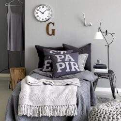 Sypialnia w nowoczesnym stylu z minimalistycznym wystrojem, białym zegarem na ścianie i poduszkami z napisami, idealne miejsce do odpoczynku i relaksu.