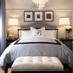 Miła i elegancka sypialnia z dużym łóżkiem Dekoracja z monogramem B, duet lamp i kwiaty, nowoczesny design, idealne miejsce do relaksu i komfortu.