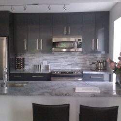 Nowoczesna kuchnia w odcieniach szarości z blatem marmurowym i sprzętem AGD, idealna do codziennego gotowania i spotkań rodzinnych.