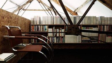 Biuro w poddaszu z półkami pełnymi książek, eleganckie miejsce do pracy i nauki, nowoczesny design, komfortowe krzesła, inspirujące środowisko do rozwoju zawodowego i edukacji optymalnej.