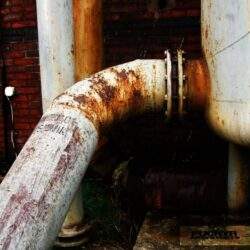 Rdzawa rdzawa rura przemysłowa na zewnątrz z metalową ścianą, przemysł, trudne warunki, infrastruktura przemysłowa, przemysłowe instalacje .